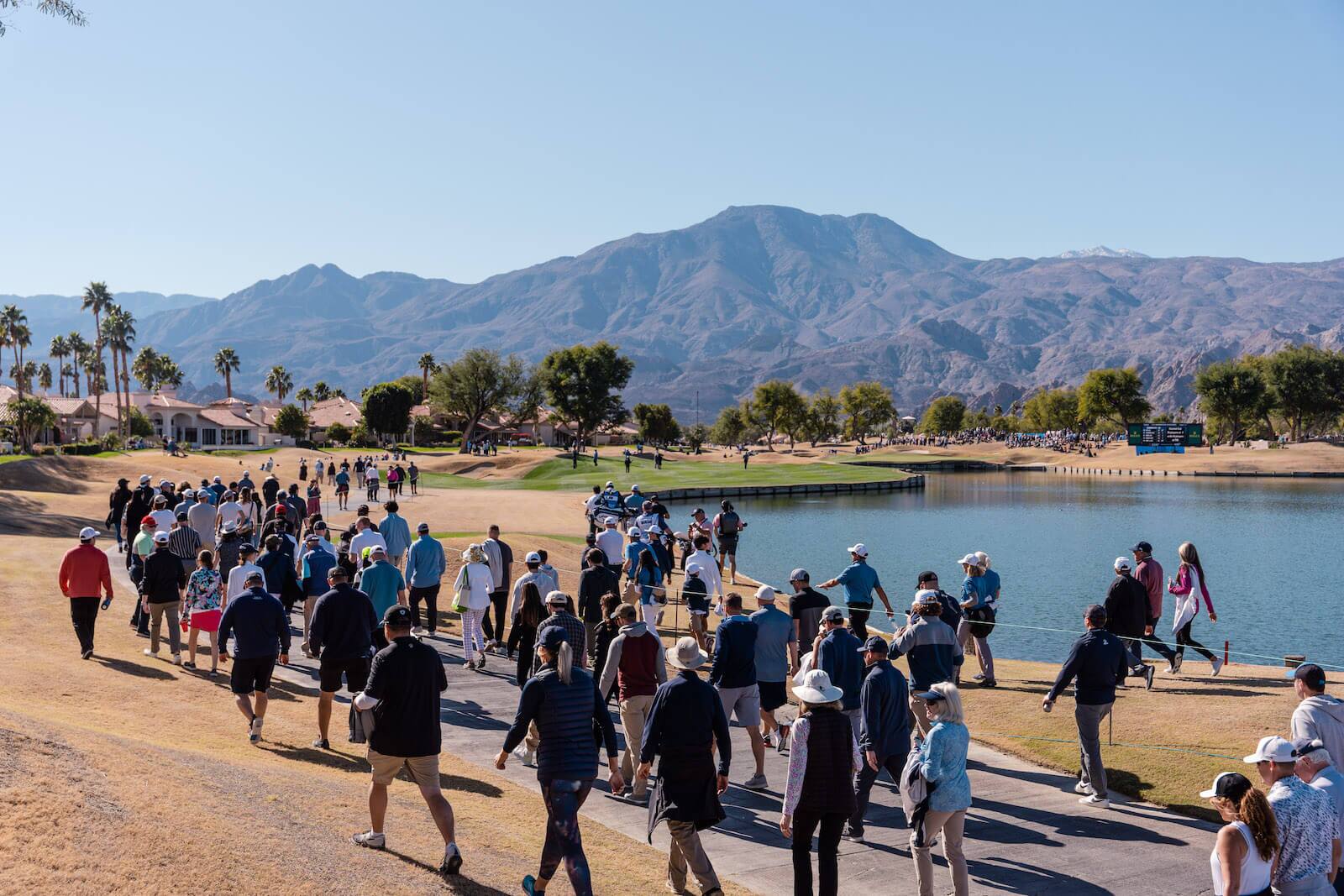 people walking along pind in golf tournament